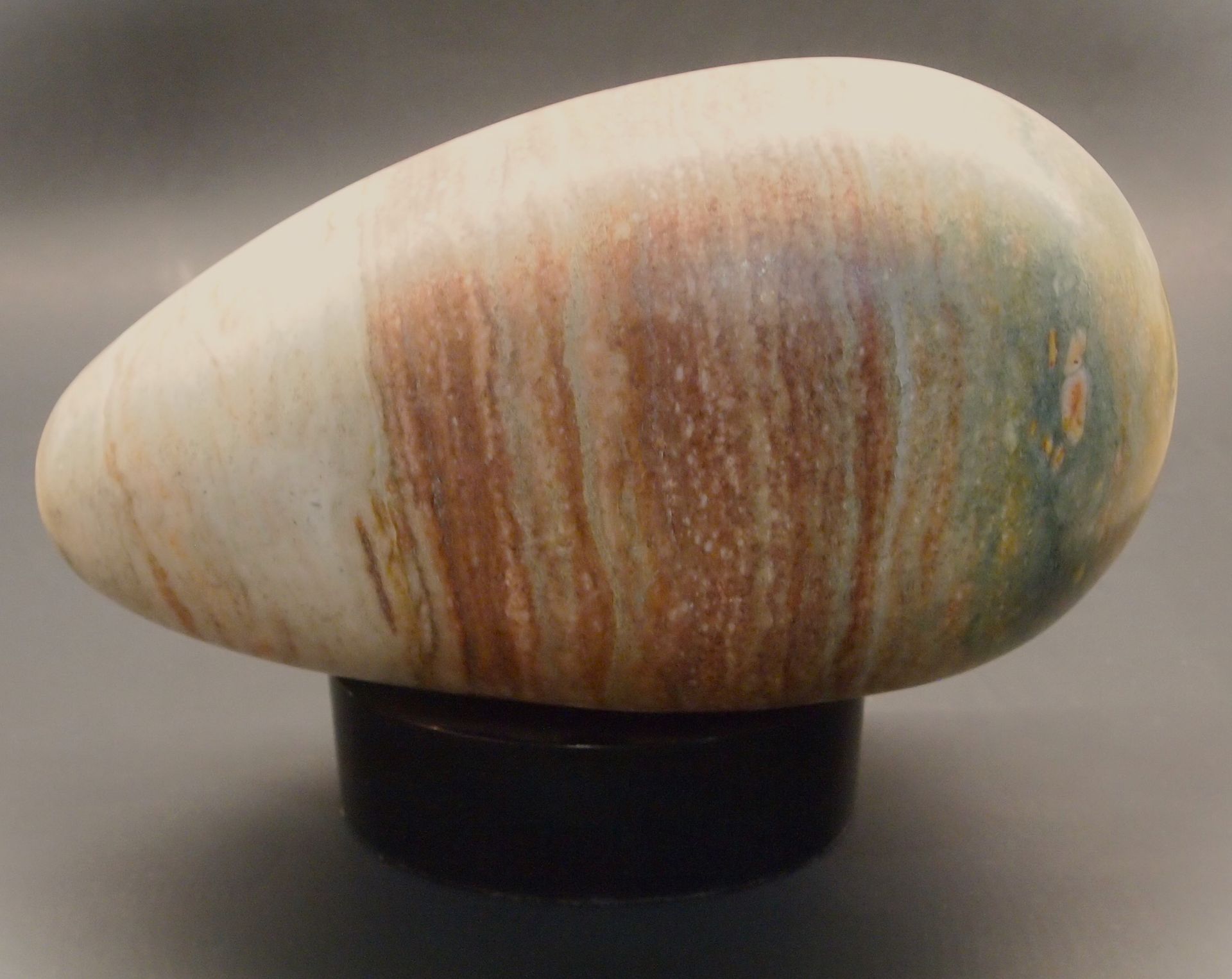 A large rock is sitting on a black base on a table.