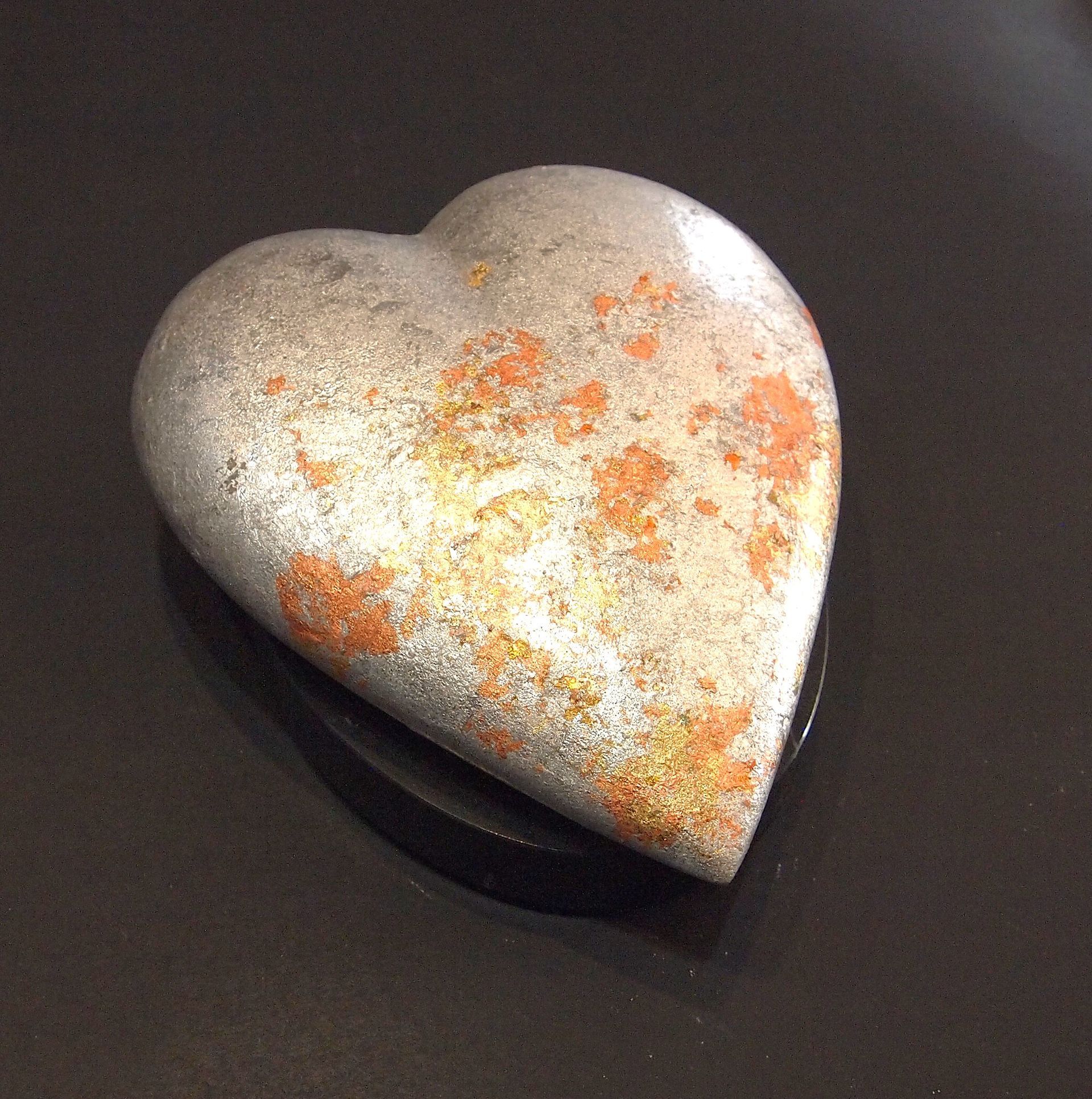 A heart shaped rock is sitting on a black surface