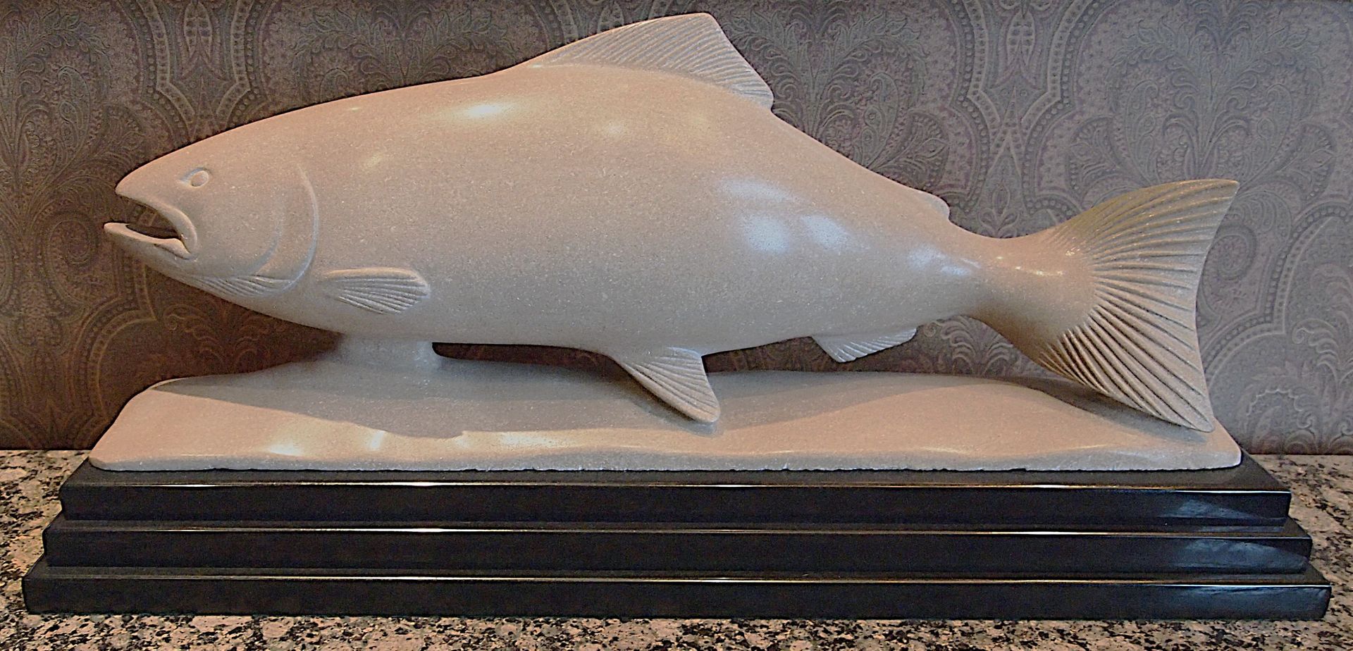 A statue of a fish is sitting on a granite counter top