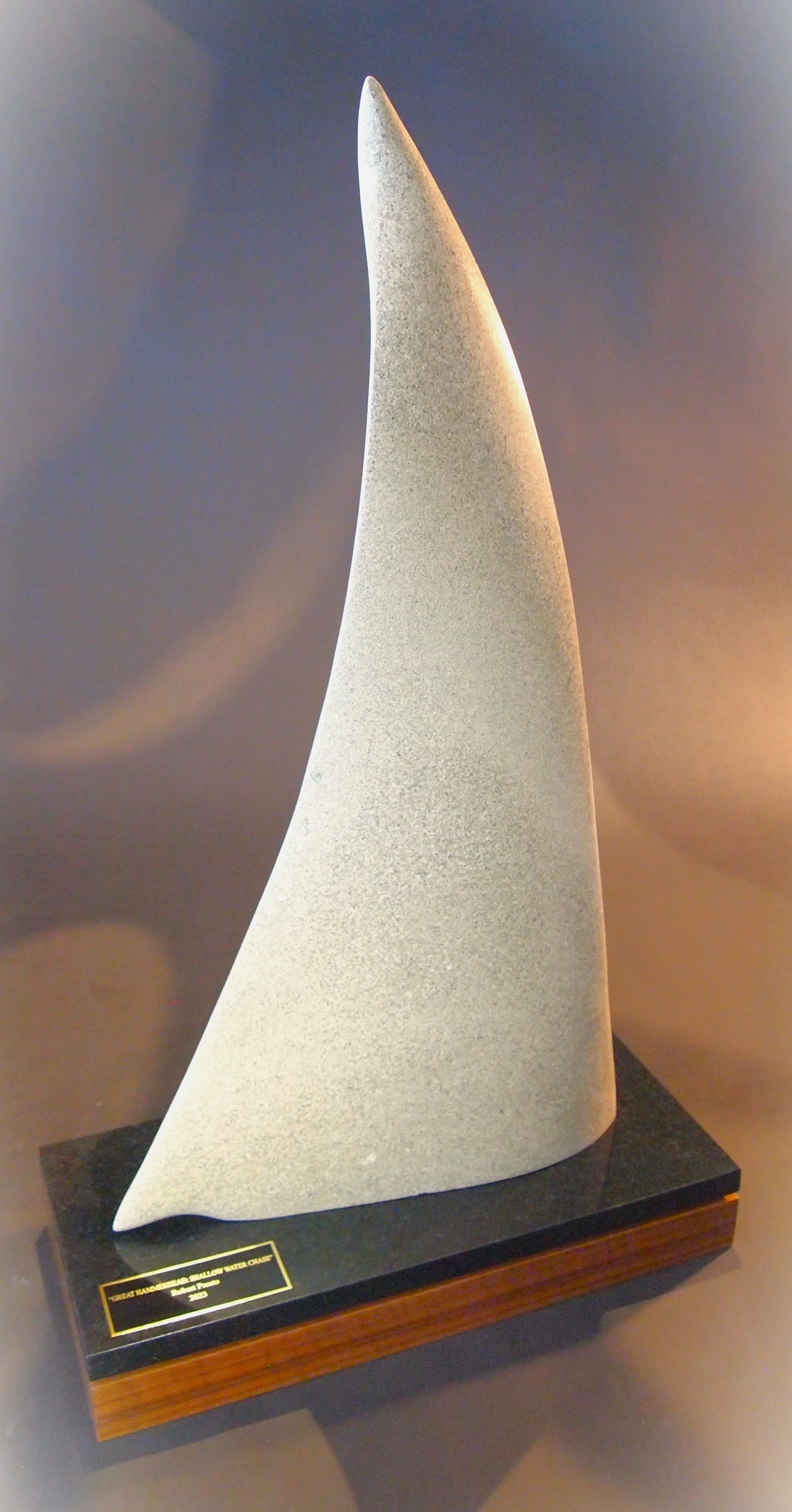 A small sculpture of a sailboat on a wooden base