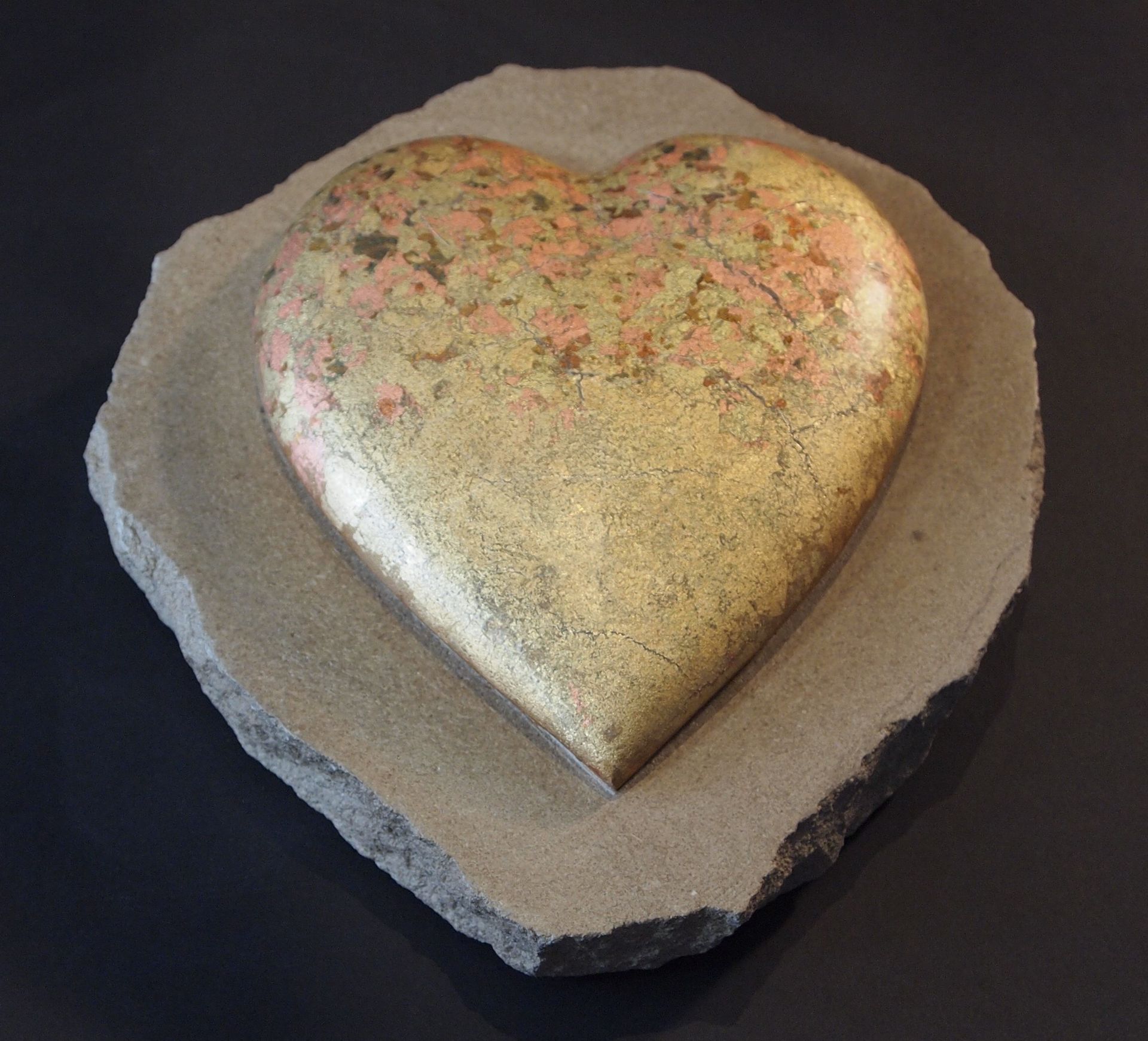 A heart shaped object is sitting on a rock