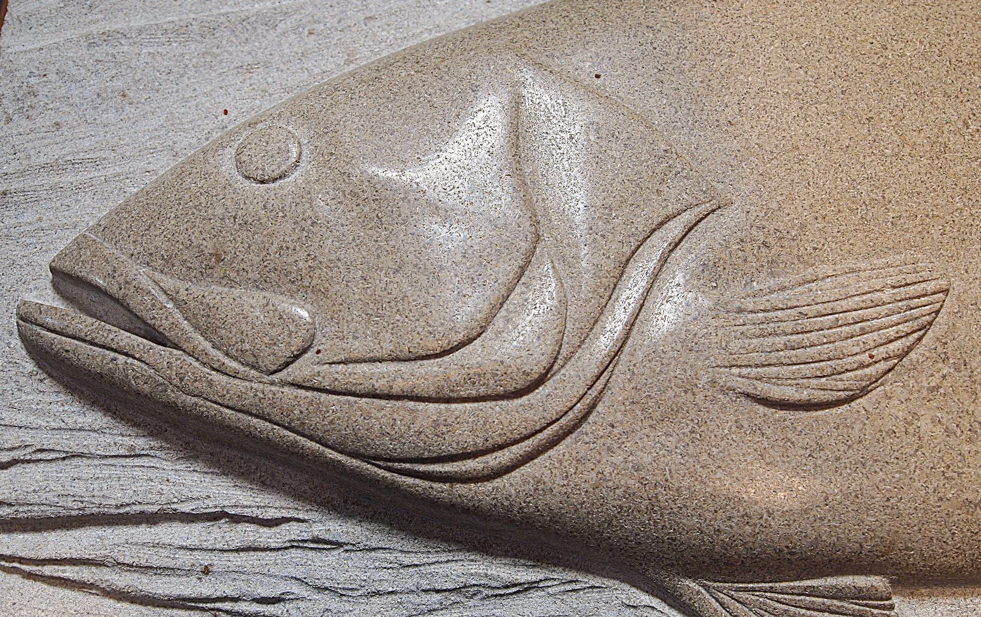 A statue of a fish 's head is carved into a rock.