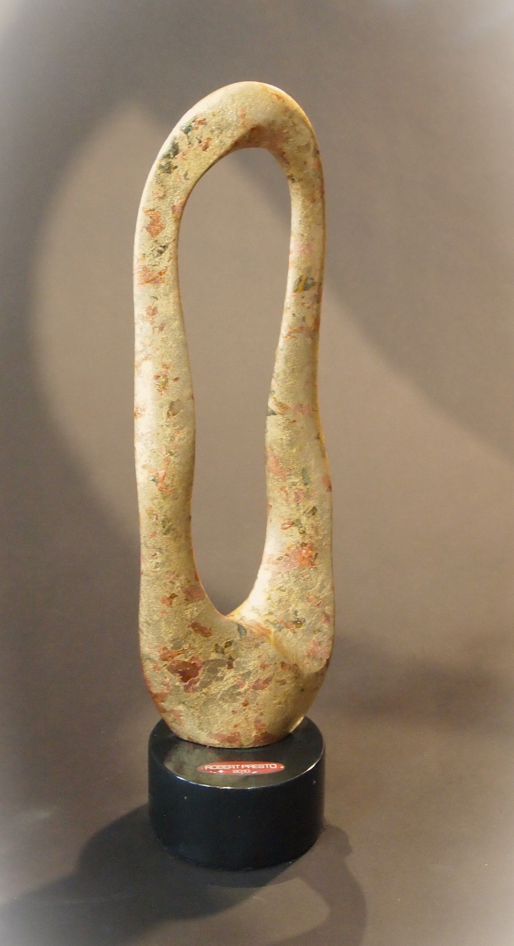 A sculpture is sitting on a black base on a table.