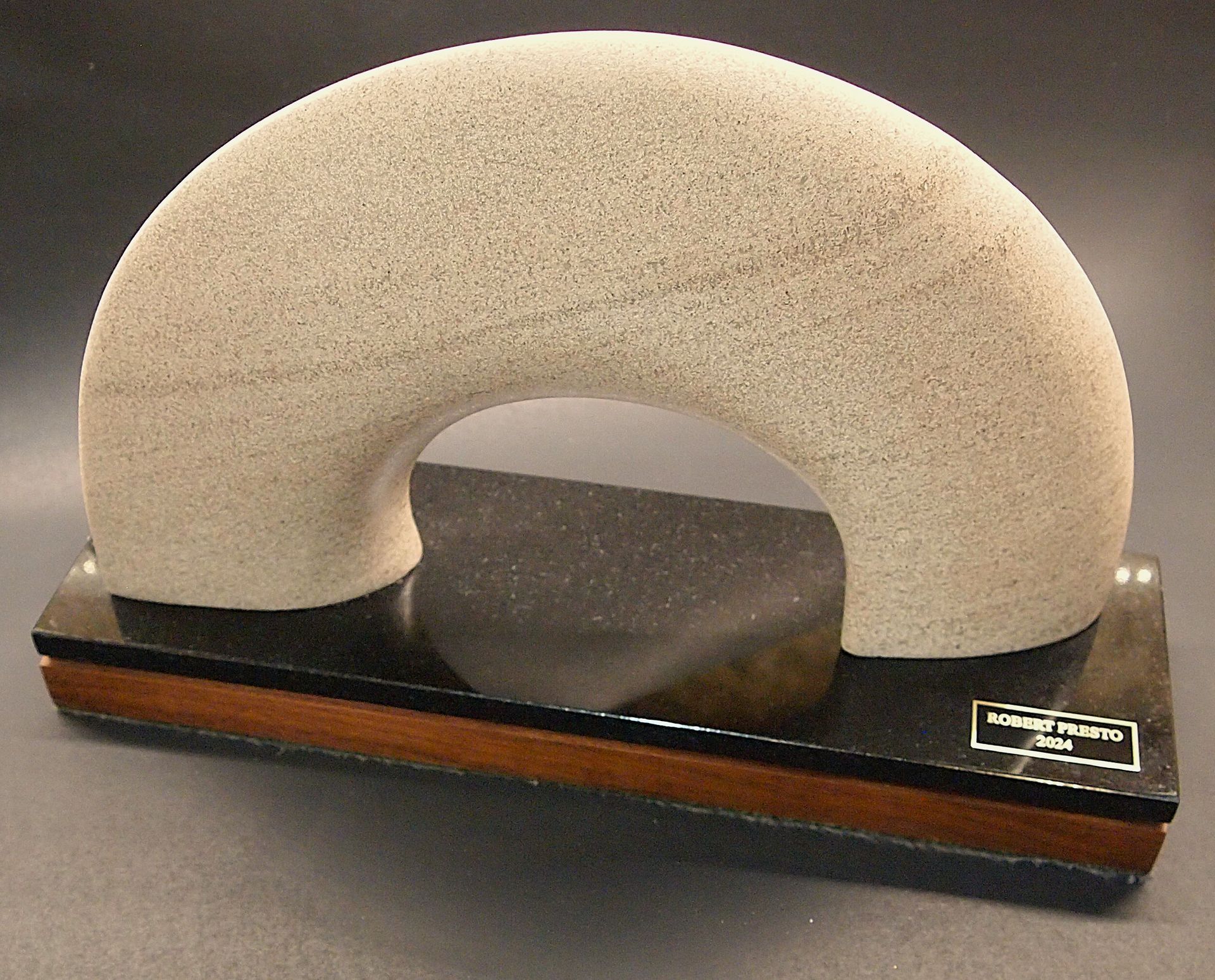 A sculpture of a rainbow is on a black base