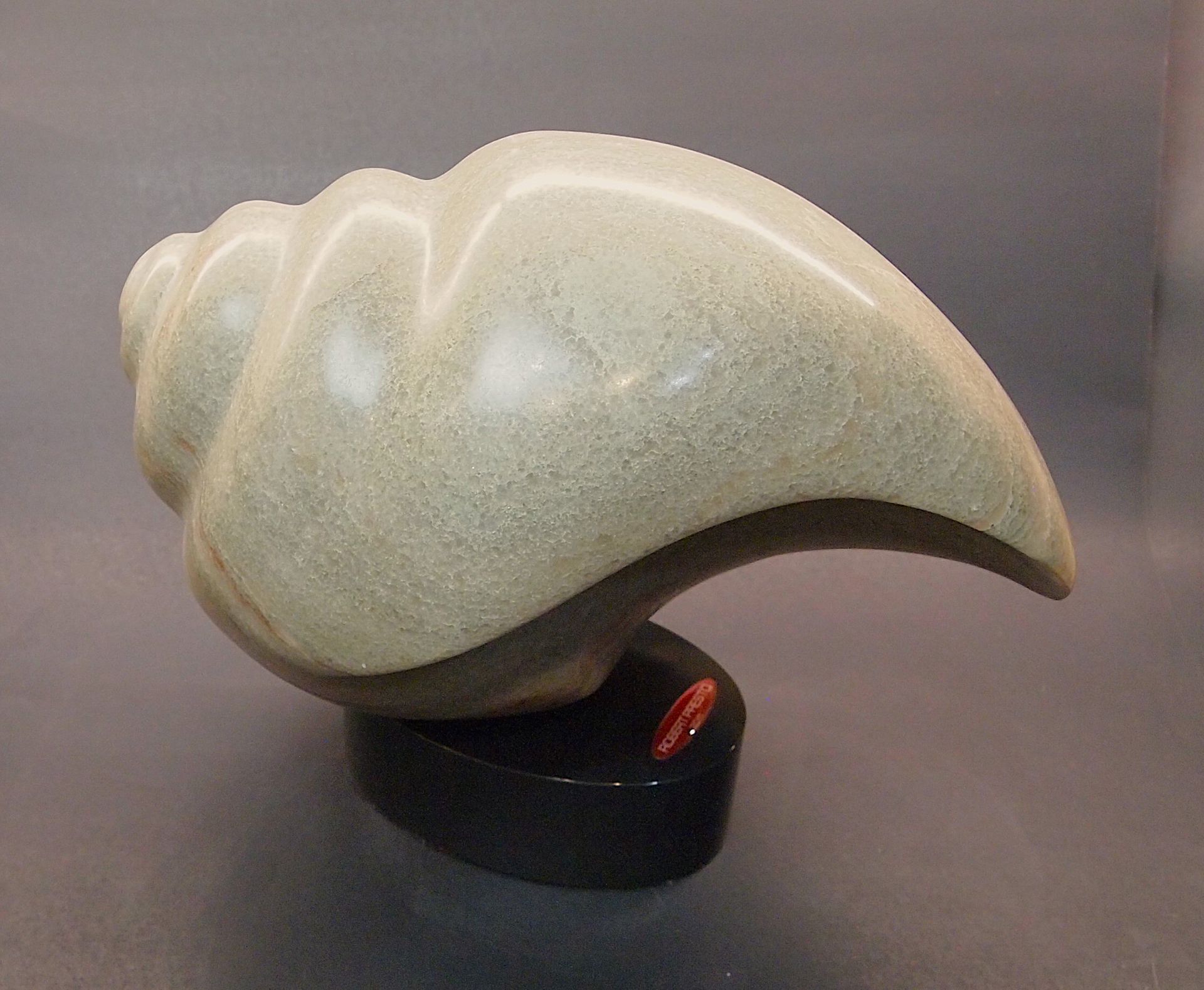 A sculpture of a sea shell on a black base