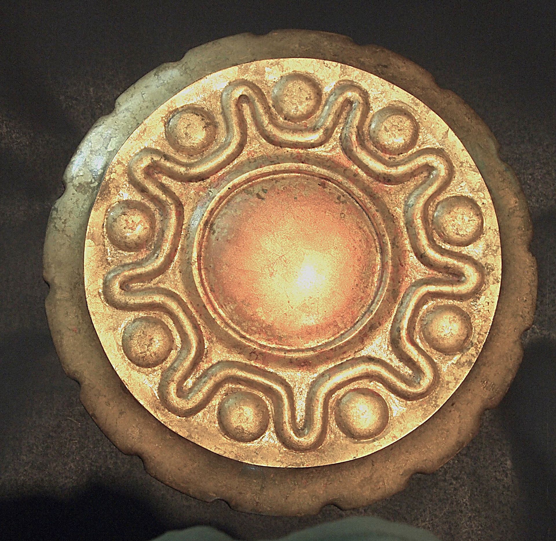 A gold plate with a circular design on it