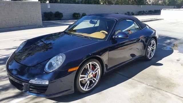 Black Porsche 911 parked on a sunny driveway, front-left view