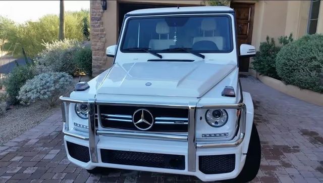 White Mercedes G-Class SUV parked in a driveway in front of a house
