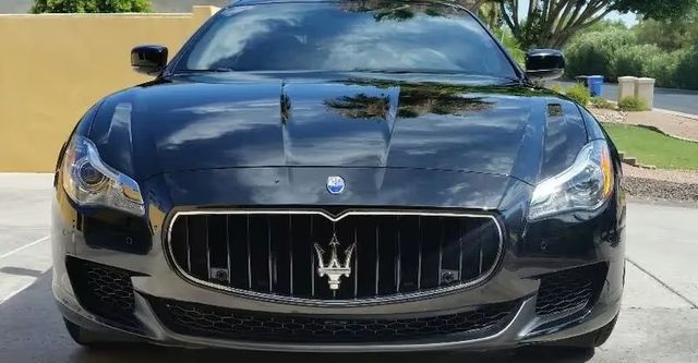 Front view of a black Maserati parked in a driveway on a sunny day