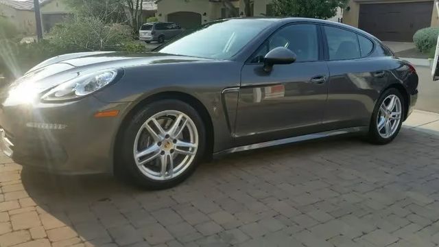 Gray sedan parked in a driveway in front of a house, side view