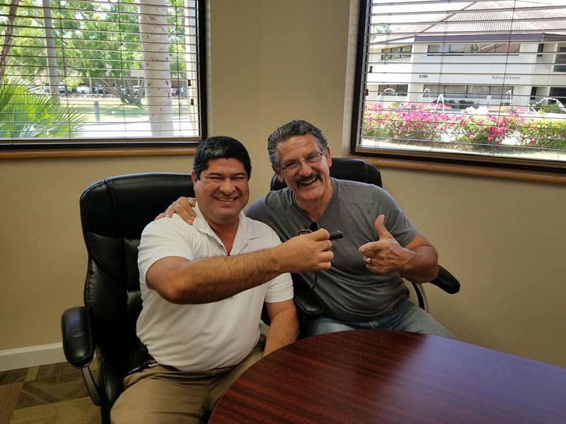 Two Smiling Men Sitting Together — Cape Coral, FL — Ordonez Realty