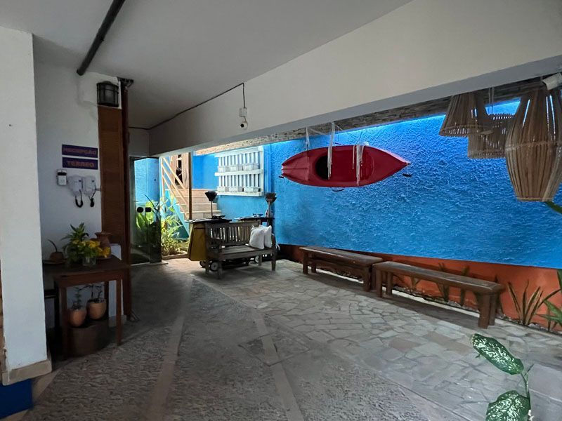 Espaço interno com paredes azuis, um caiaque vermelho, bancos de madeira e decoração natural.