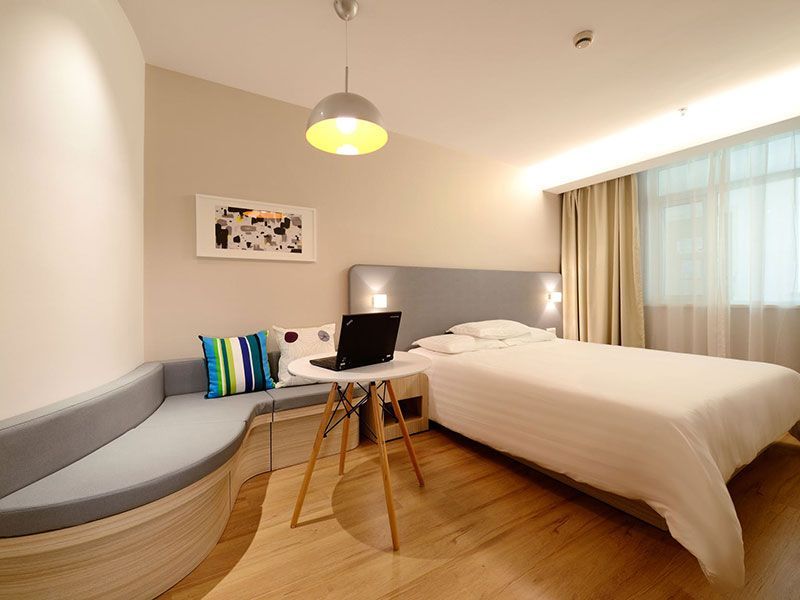 Quarto com cama, mesinha com espaço para laptop, sofá embutido e janela.