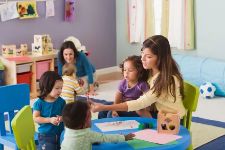 A woman is sitting at a table with a group of children