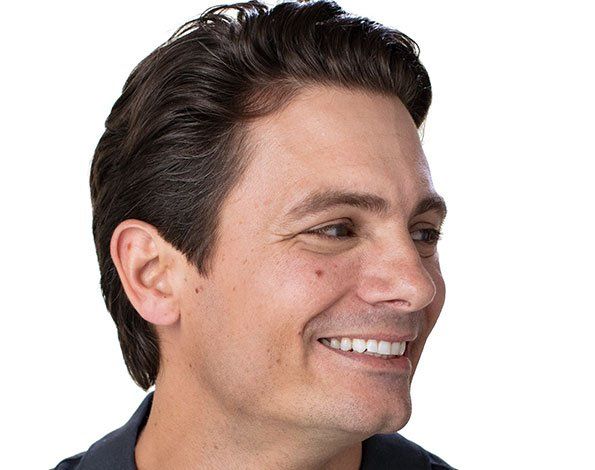 Smiling man with dark hair, looking right.