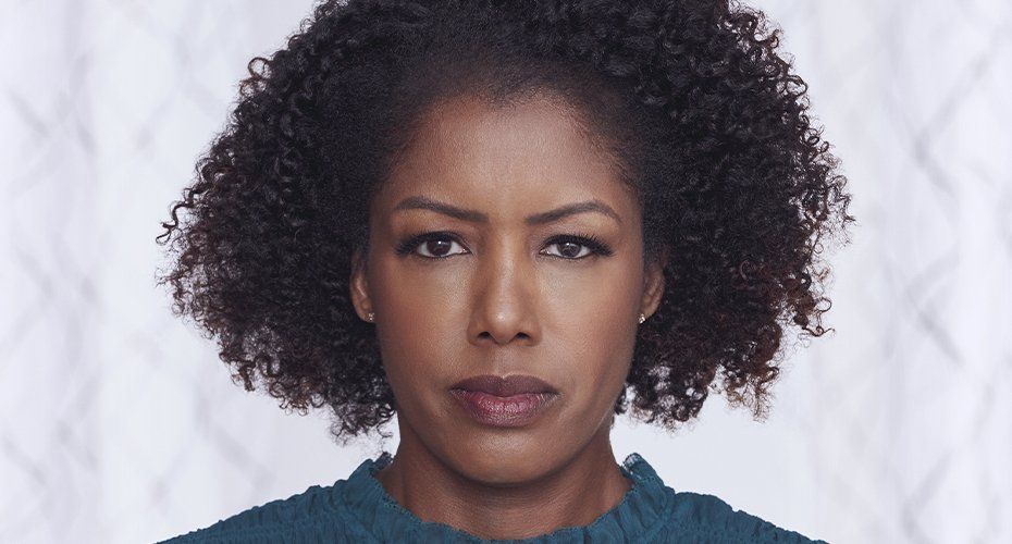 Black woman with curly hair, serious expression, against a white background.