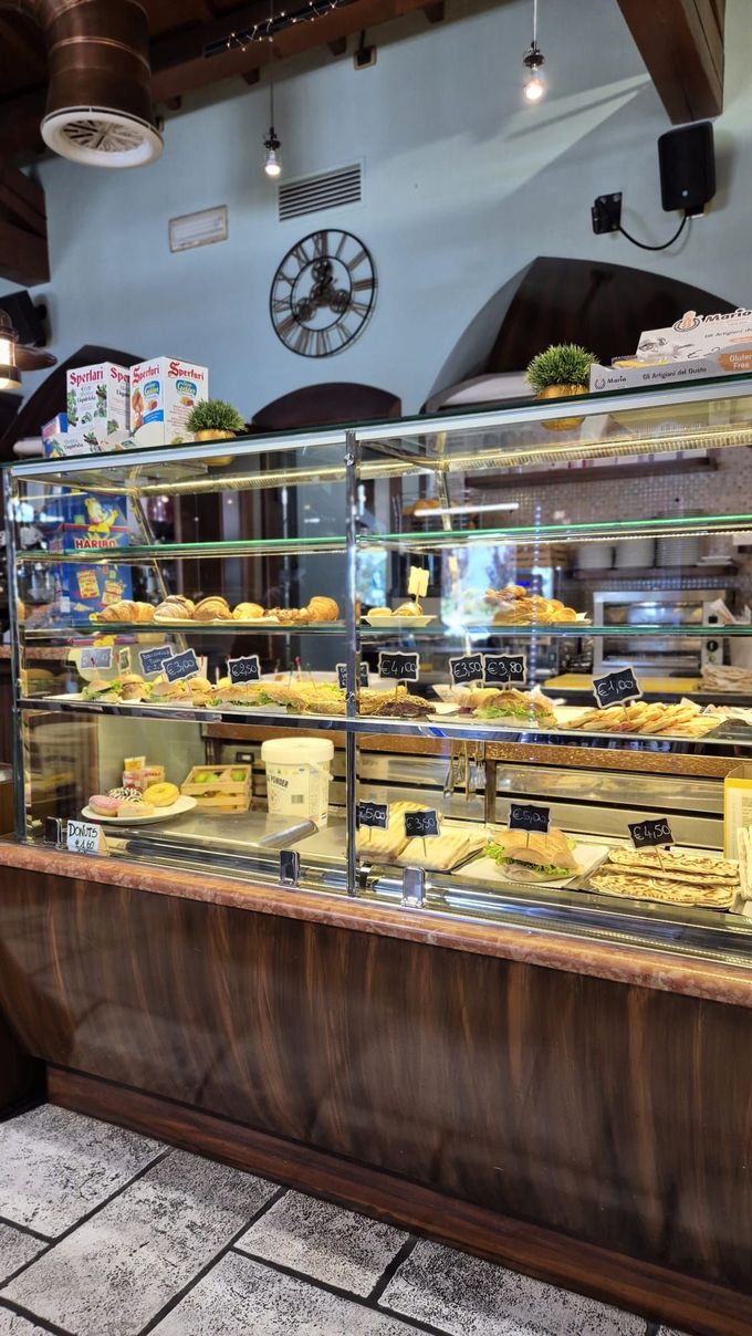 Una vetrina di panetteria piena di cibo e un orologio sul muro.