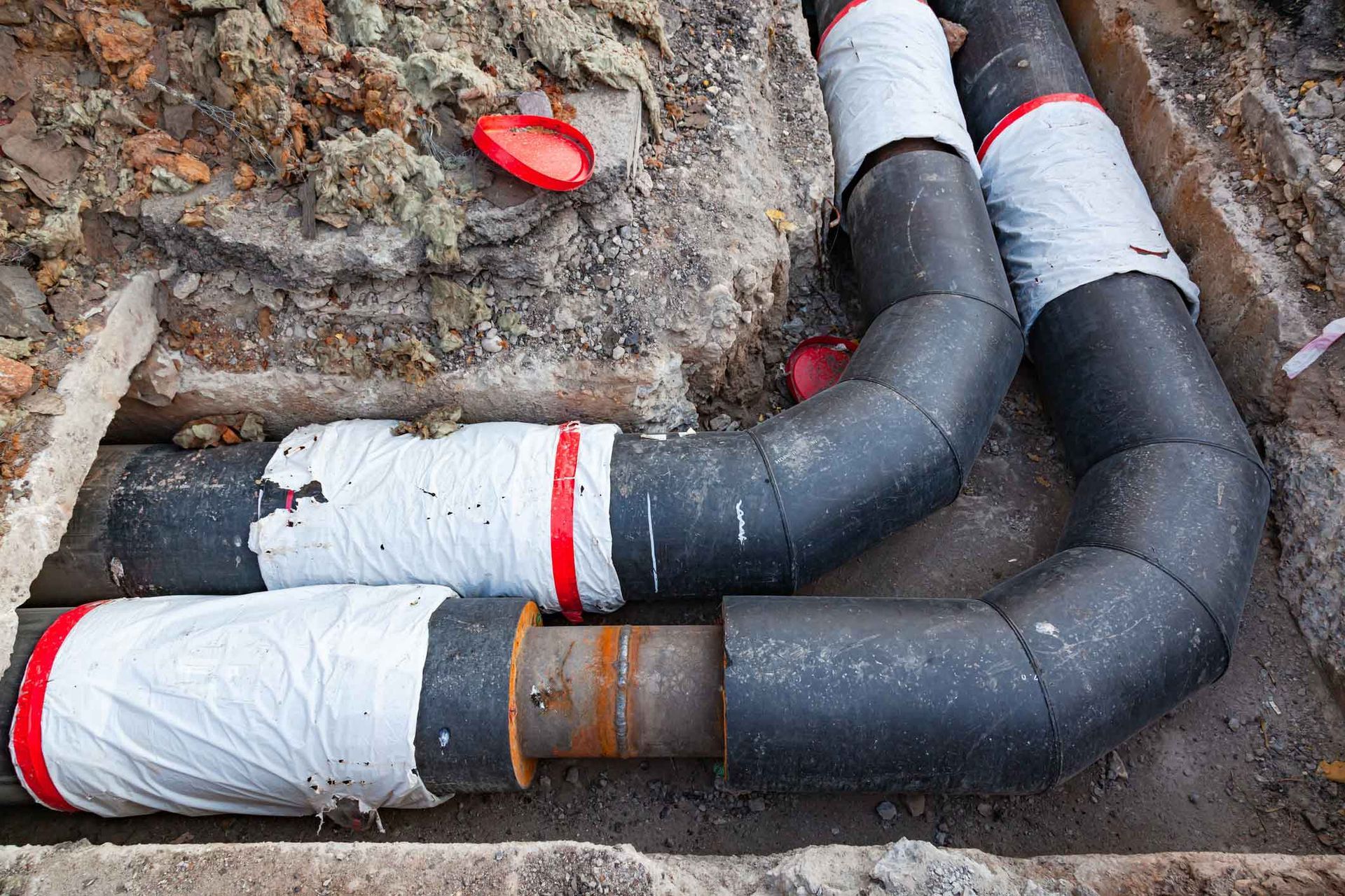 A bunch of pipes are laying in the dirt.