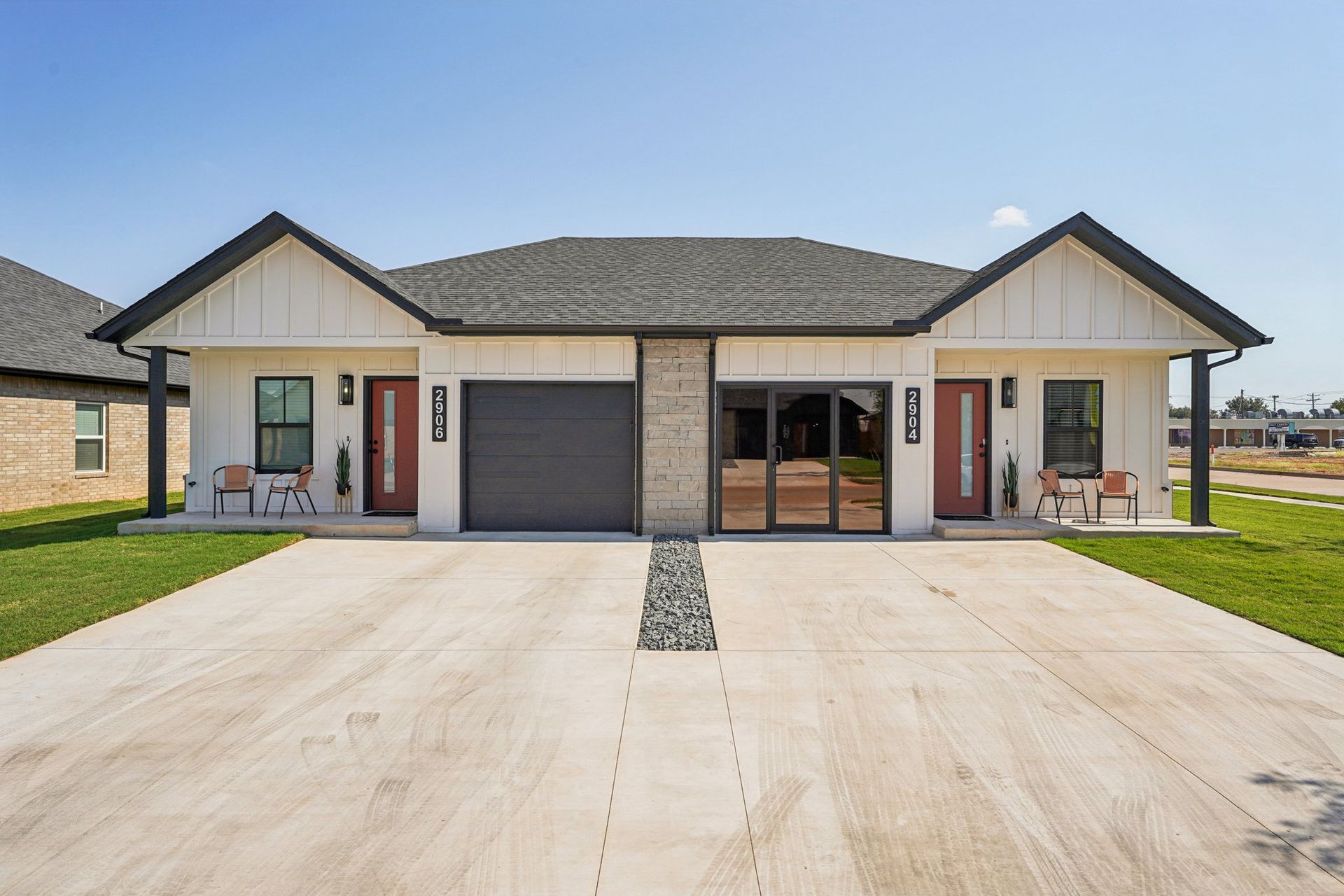 Two modern duplexes with white siding, dark roof, and concrete drive.