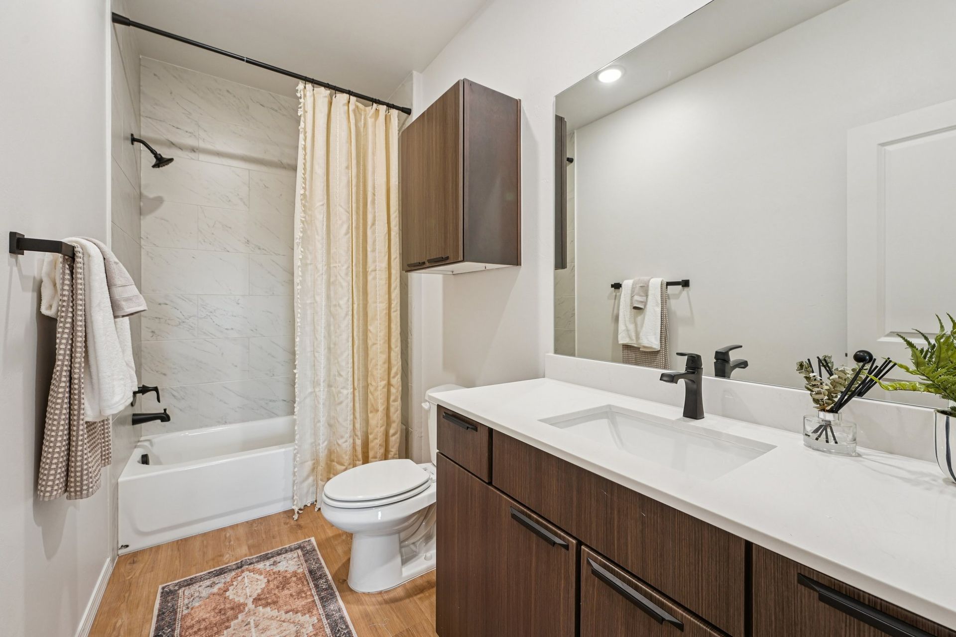 Bathroom with white vanity, dark brown cabinets, tub, shower, and toilet.
