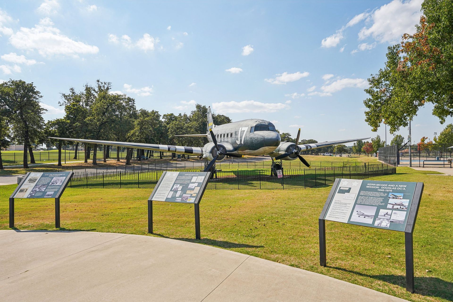 Large, parked airplane with informational signs on green lawn under blue sky.