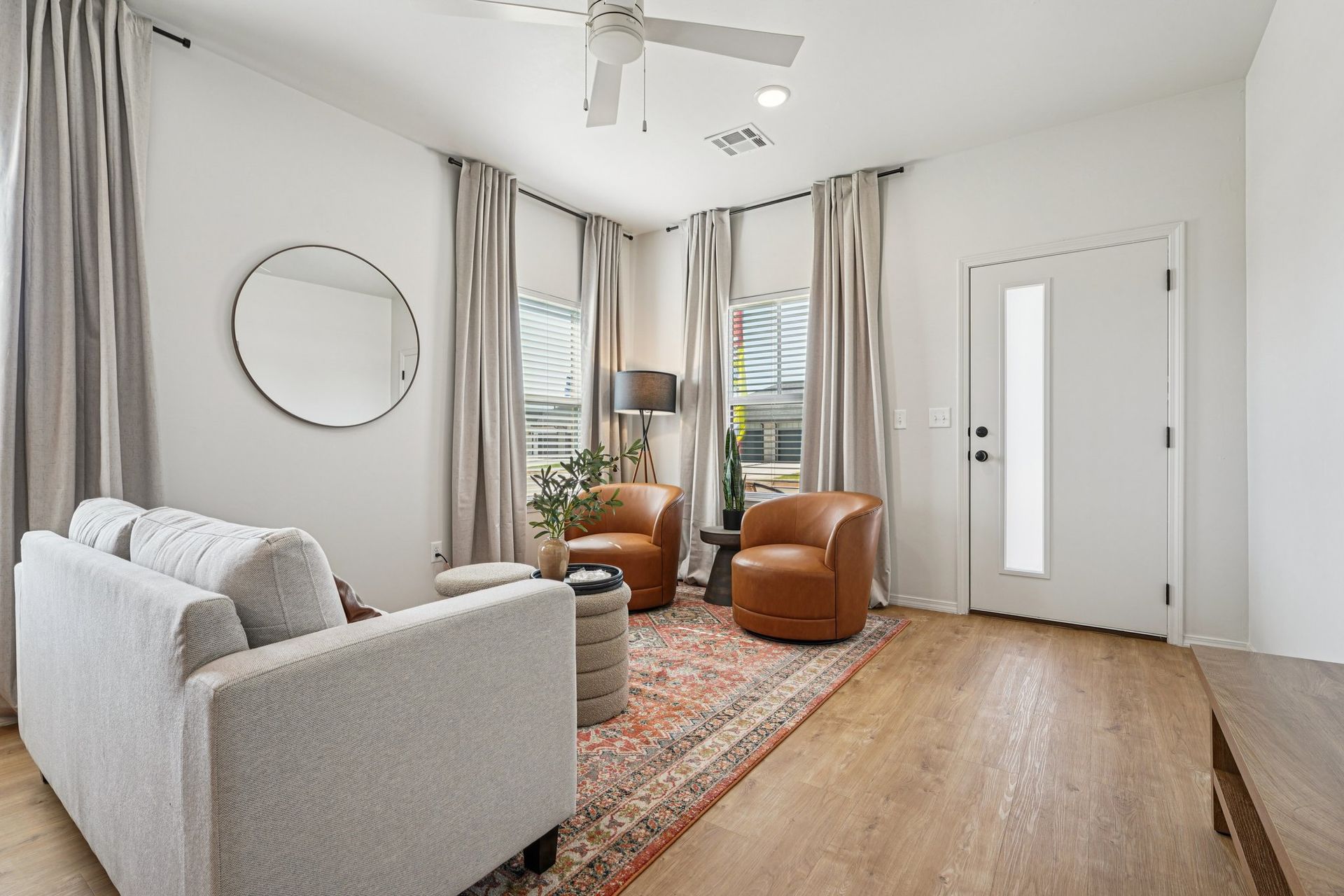 Living room with neutral tones, light wood floors, and leather armchairs.