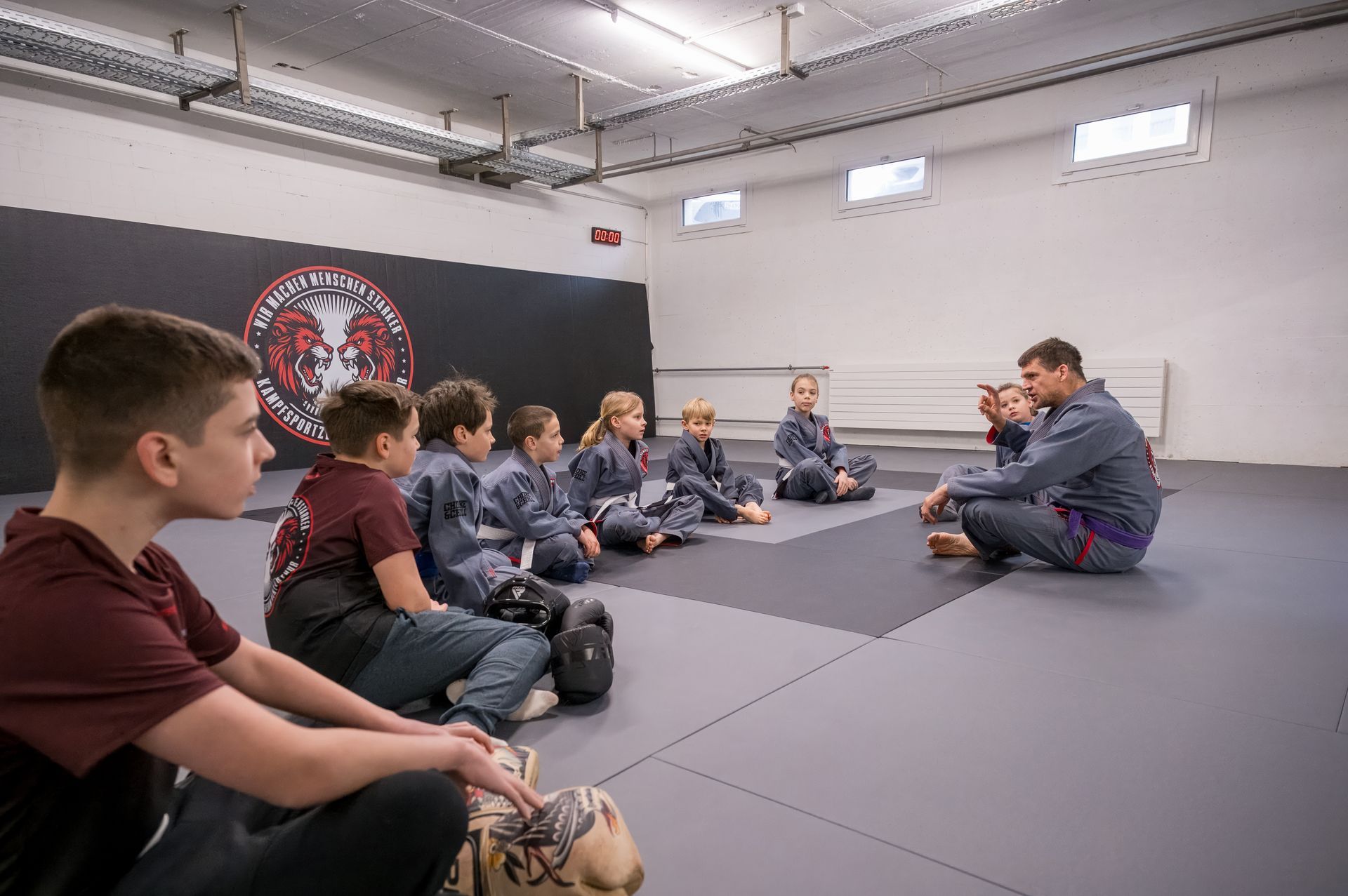 Viele Personen sitzen im Kreis und hören einem Trainer zu