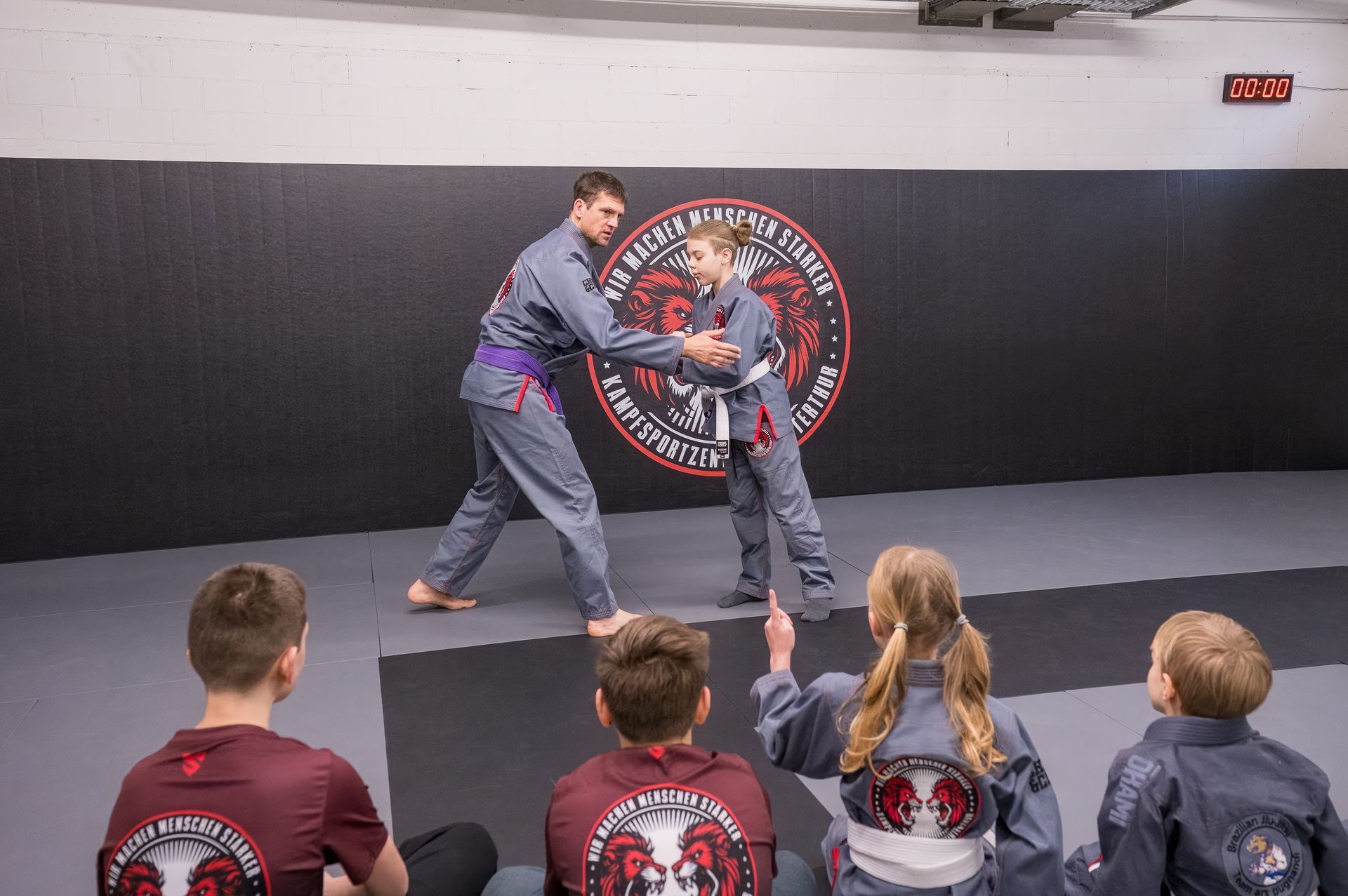 Zwei junge Personen üben in einem Fitnessstudio Kampfsport.