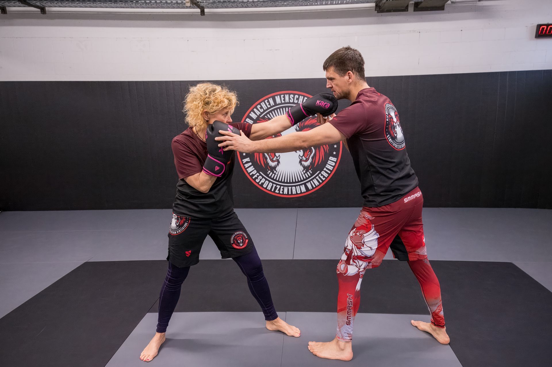 Zwei Männer kämpfen in einem Fitnessstudio und einer von ihnen trägt Boxhandschuhe.