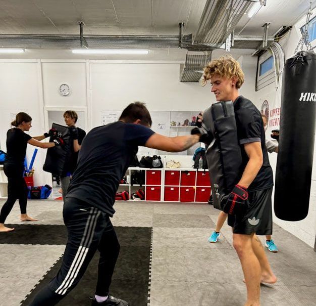 Eine Gruppe von Leuten trainiert in einem Fitnessstudio Boxen.