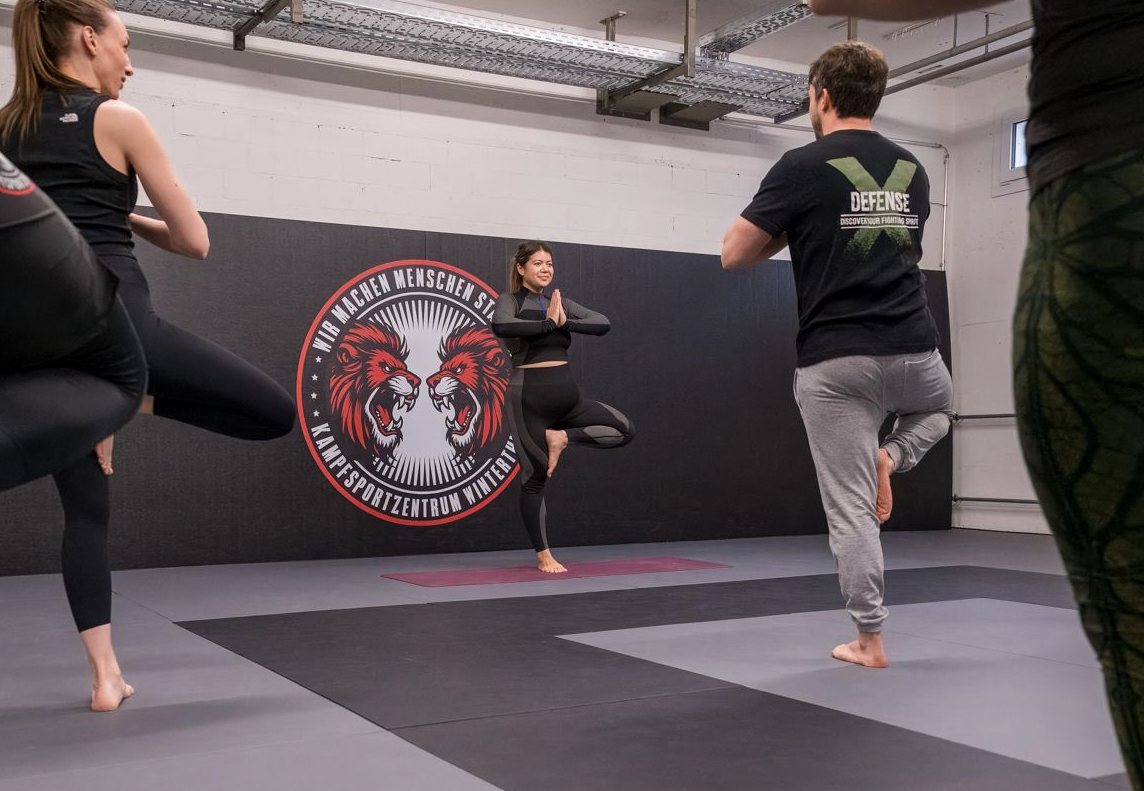 Eine Gruppe von Menschen macht Yoga in einem Kampfsportzentrum.