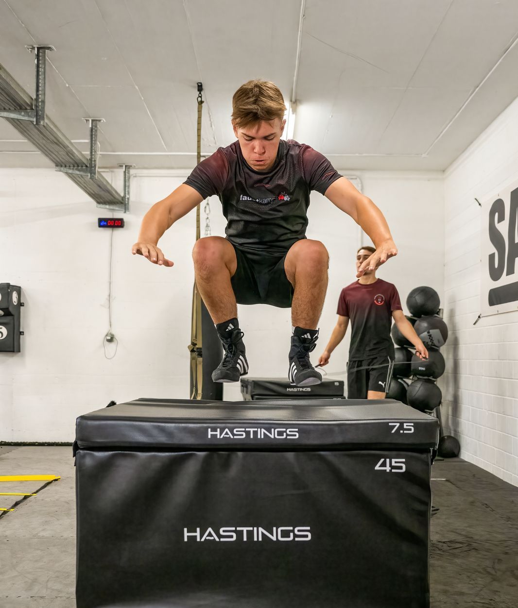 Ein Mann springt über eine Hastings-Box in einer Turnhalle