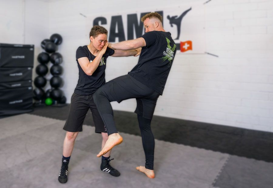 Zwei Personen üben in einem Fitnessstudio Kampfsport.