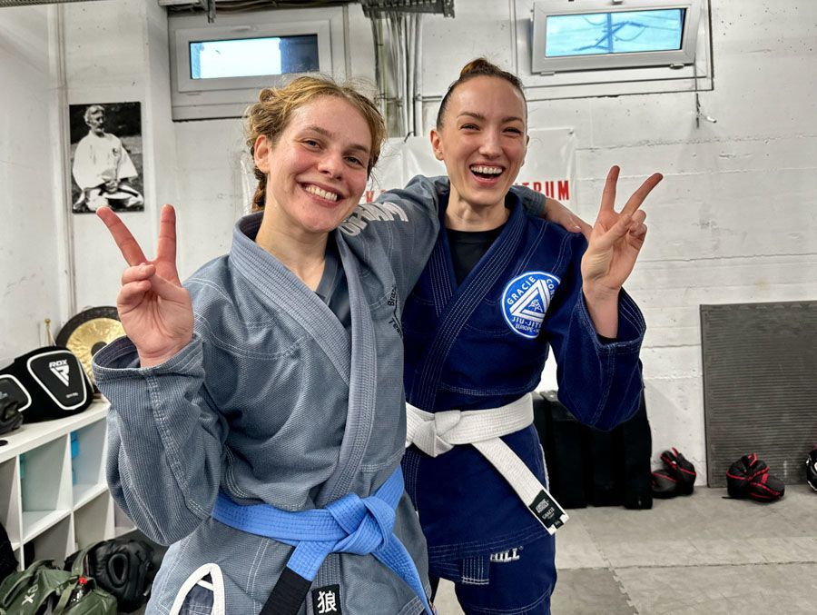 Zwei Frauen in Karateuniformen machen ein Peace-Zeichen.