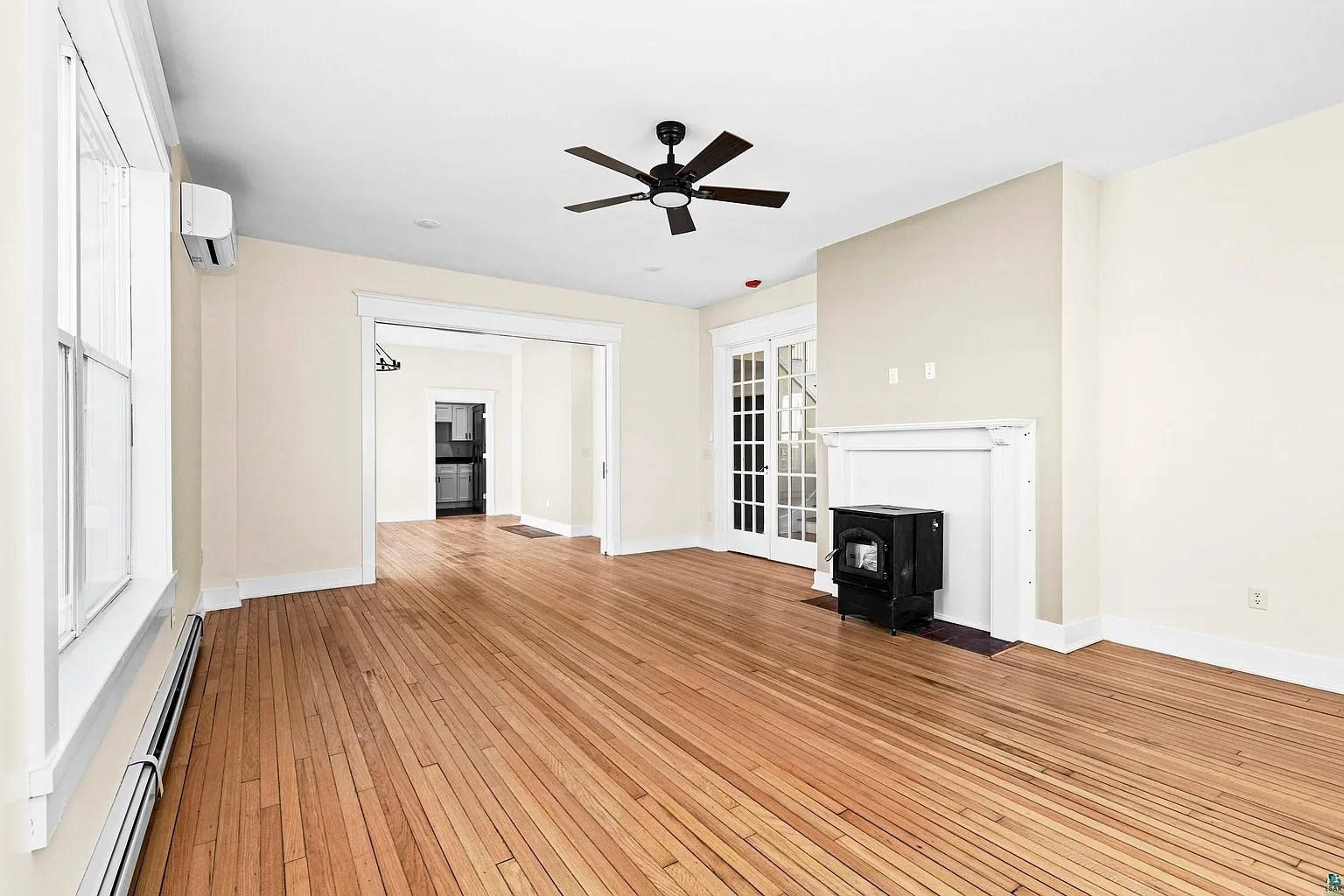 An empty living room with hardwood floors and a ceiling fan.