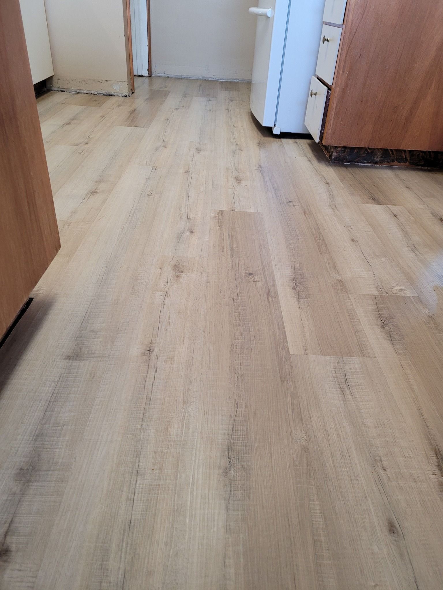 A kitchen with hardwood floors and wooden cabinets.