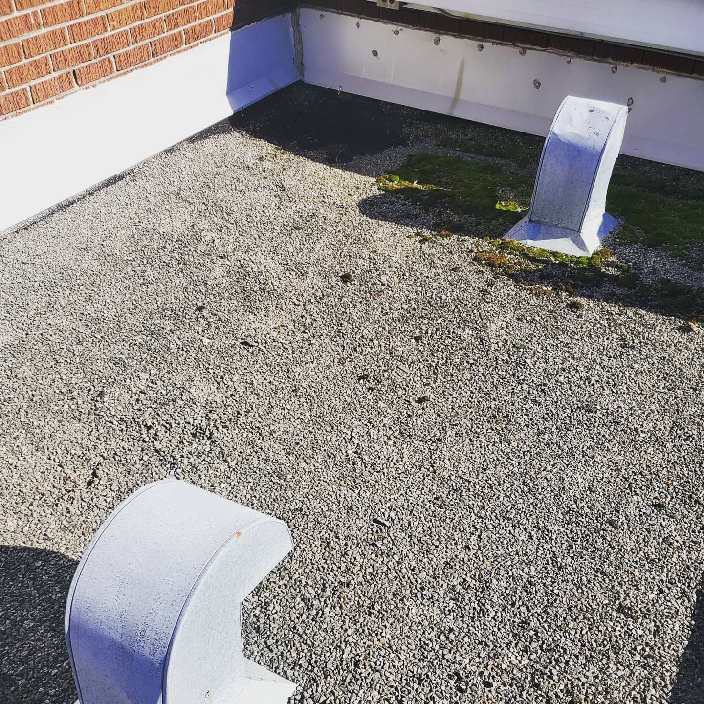 Toit avec gravier, blocs blancs et mur de briques. Journée ensoleillée.