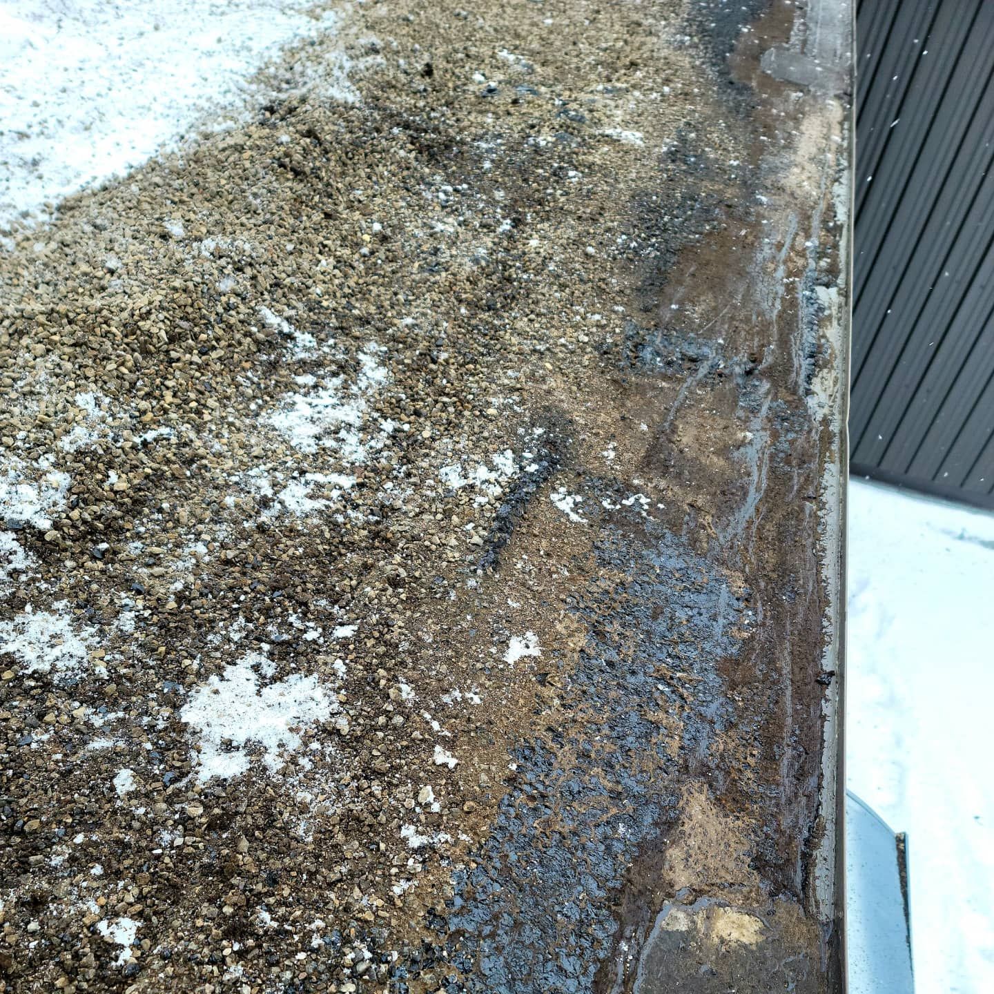 Gros plan d'une colonne en béton patiné et humide avec des taches sombres et une surface grise.