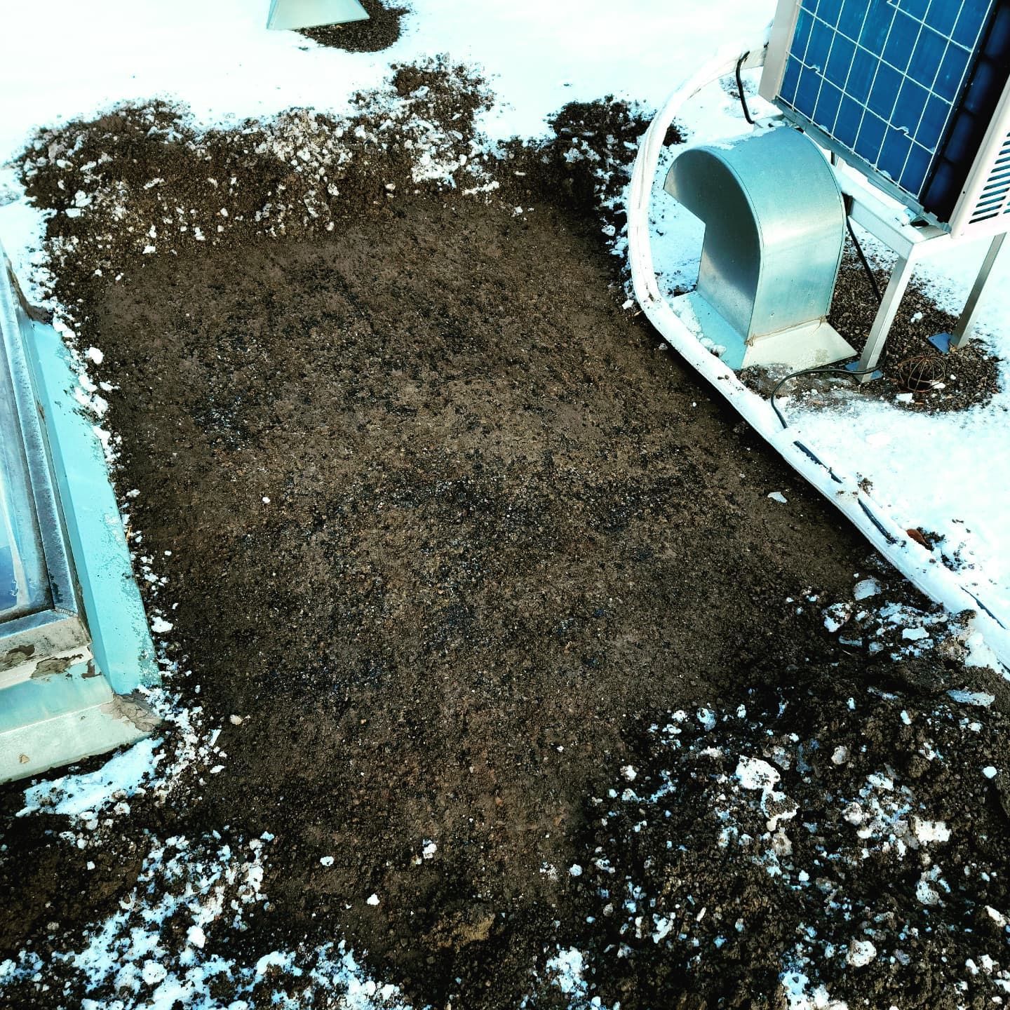 Tache de saleté sur le toit, près de la neige, d'un panneau solaire et d'un évent métallique courbé.