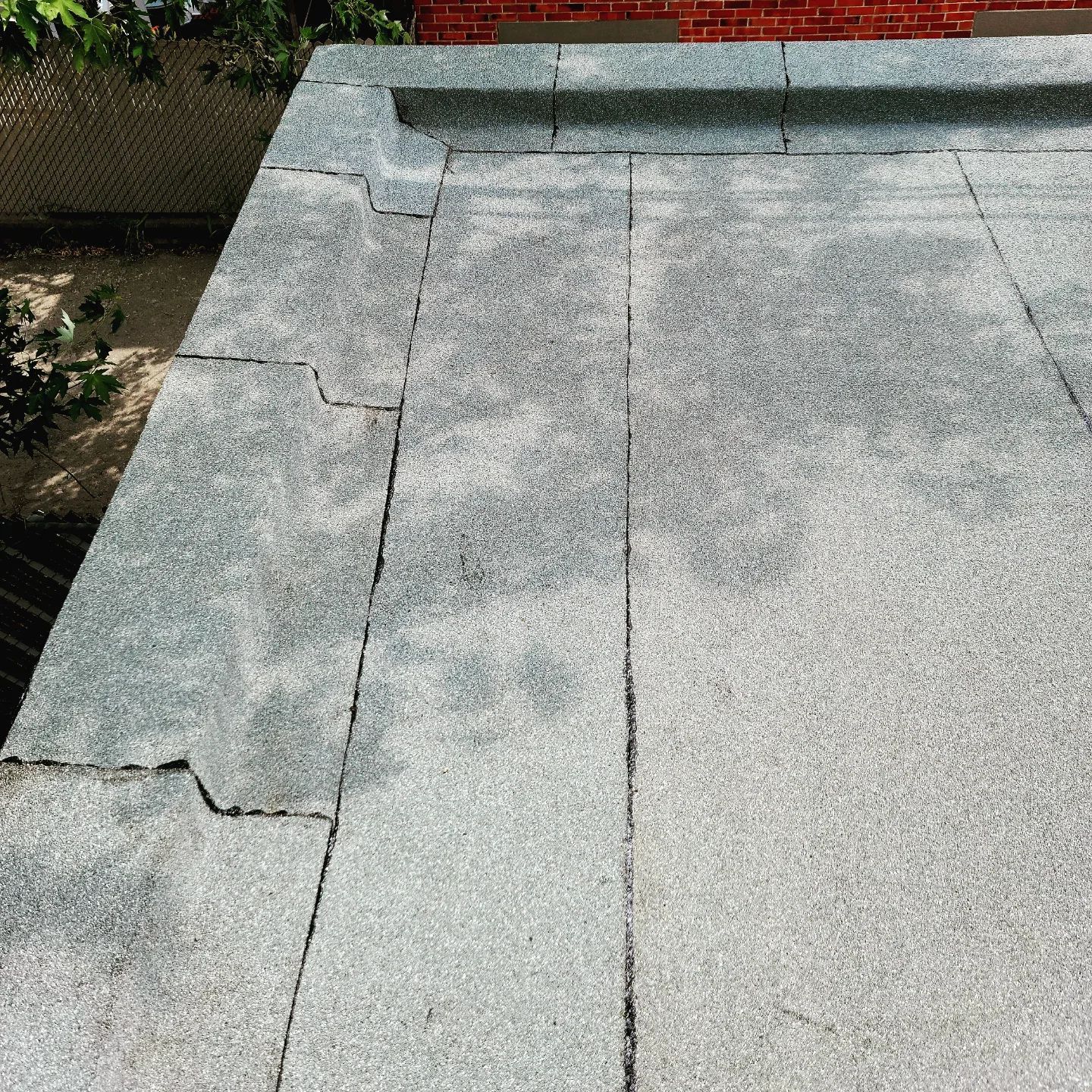 Toit plat gris avec coutures apparentes et une petite fissure.