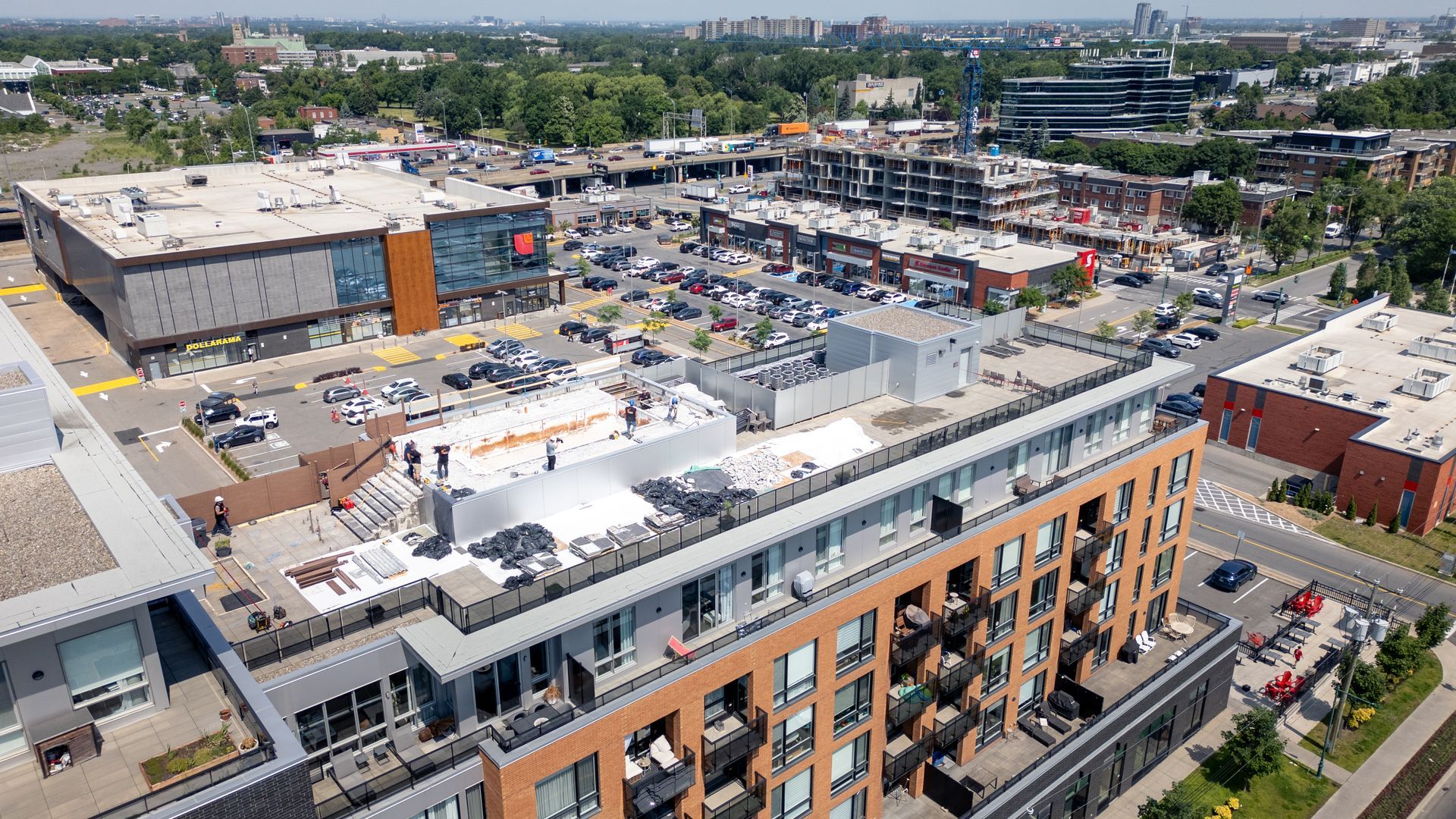 Vue aérienne d'une zone commerciale avec des bâtiments, des parkings, des routes et des voitures.
