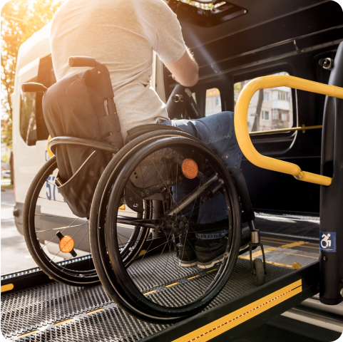 A man in a wheelchair is getting out of a bus.
