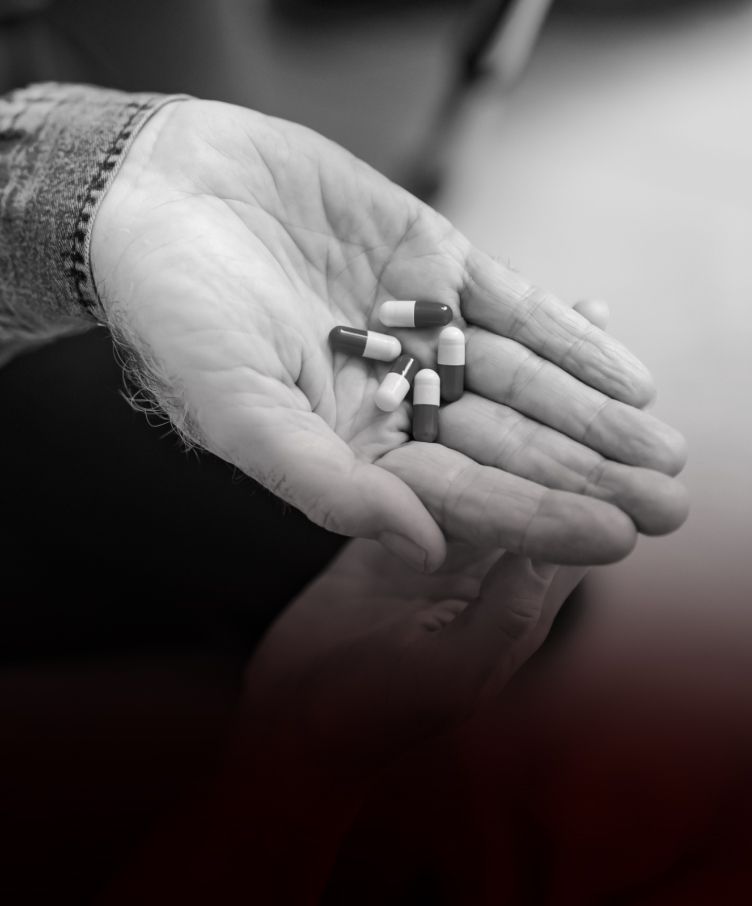 A person is holding a handful of pills in their hand.