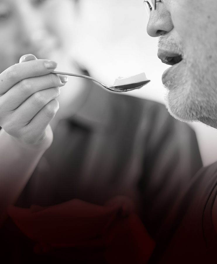 A black and white photo of a man eating from a spoon