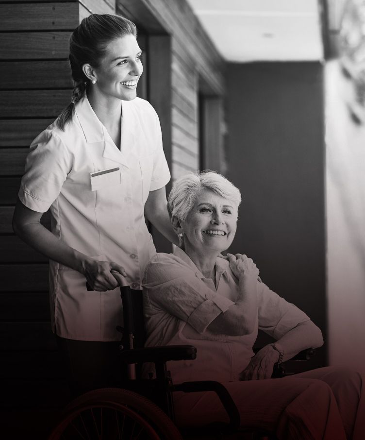 A nurse is standing next to an older woman in a wheelchair.