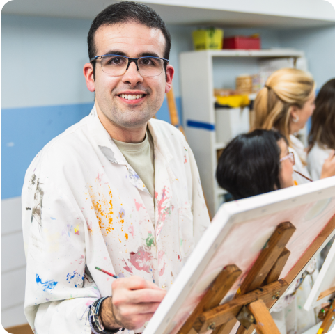 A man is painting on a canvas on an easel