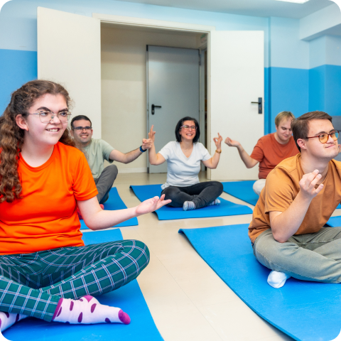 A group of people are sitting on yoga mats in a room.