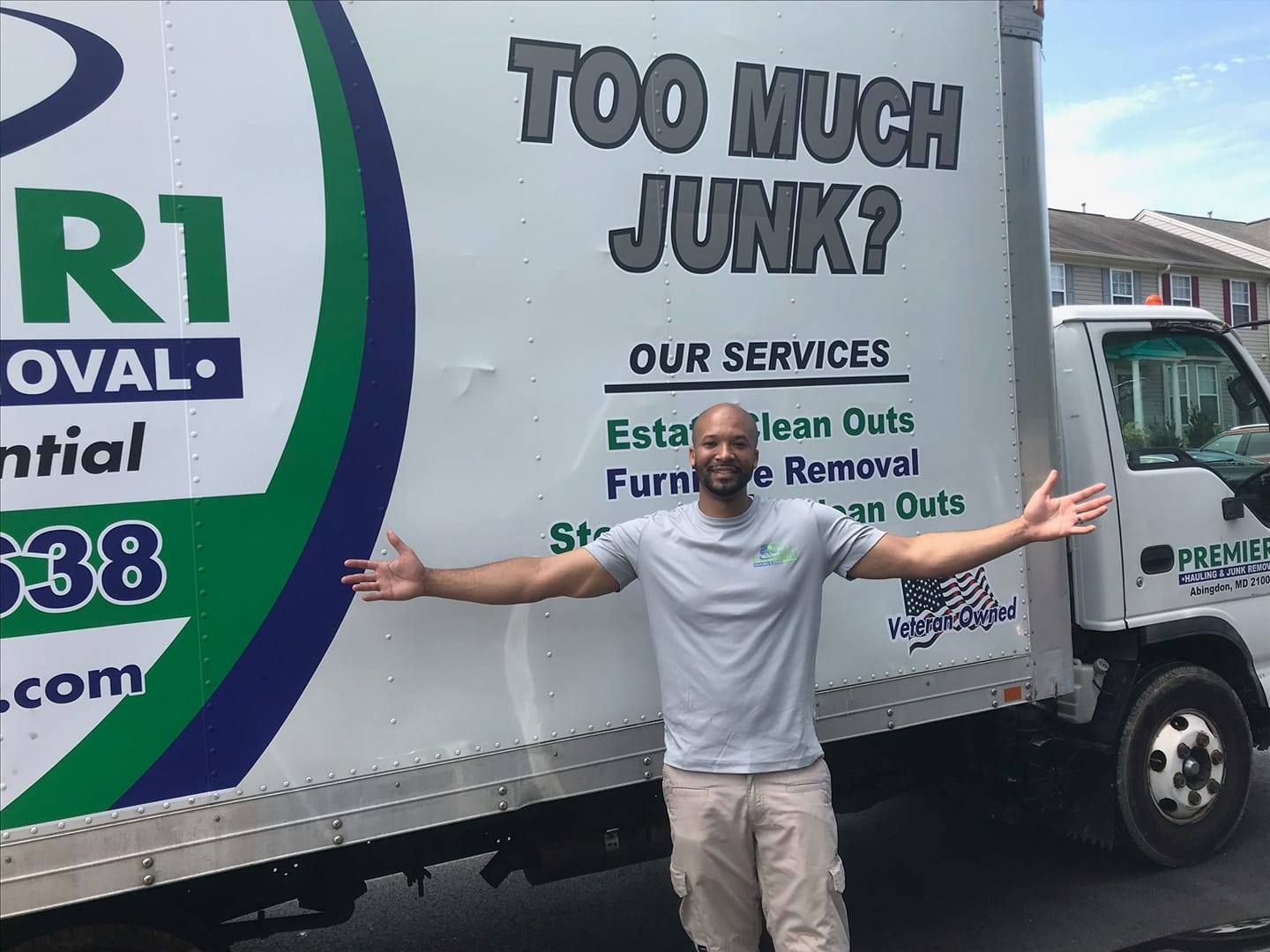 A man is standing in front of a truck that says too much junk