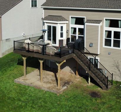 A wooden deck with a newly replaced, lighter-colored rectangular section in the center, surrounded by older, dark wood.