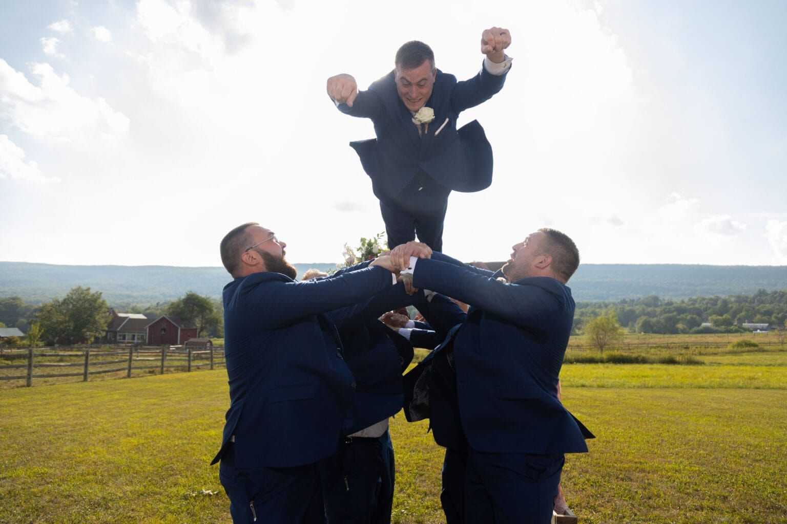 The groom is being lifted in the air by his groomsmen.